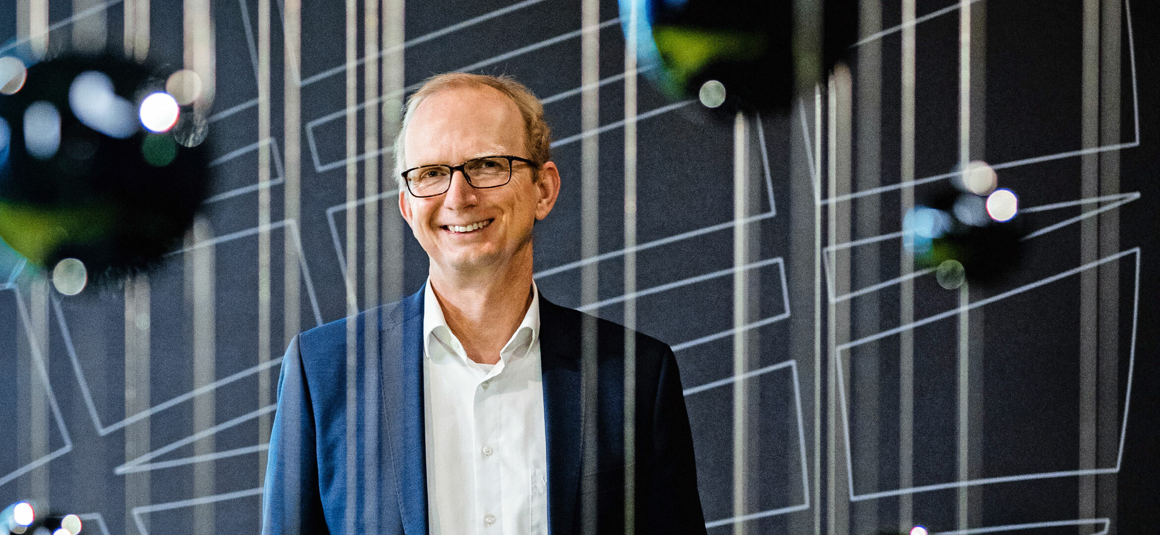 Foto von Dr. Tobias Lösche-ter Horst. Der Leiter der Abteilung „Battery Innovation“ lacht aus einer Brille in die Kamera.