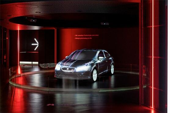 Foto eines Seat Modells, das im Seat Pavillon ausgestellt wird. Der Wagen steht auf einer runden Plattform in einem rot-schwarzen Raum.