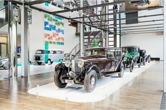 Foto historischer Bentley im Ausstellungsraum ZeitHaus. Über den Autos befinden sich Metallgestänge, eine Treppe führt auf eine höhere Ebene.