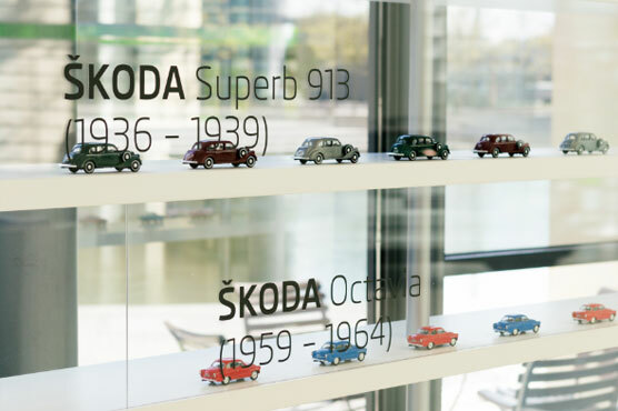 Foto einer Miniatursammlung an historischen ŠKODA Fahrzeugen hinter einer Glasvitrine im ŠKODA Pavillon.