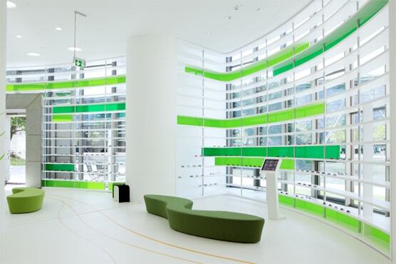 Foto einer Lounge im SKODA Pavillon. Zu sehen sind grüne organische Sitzinseln neben Fensterfronten, in die grüne Streifen eingelassen sind.