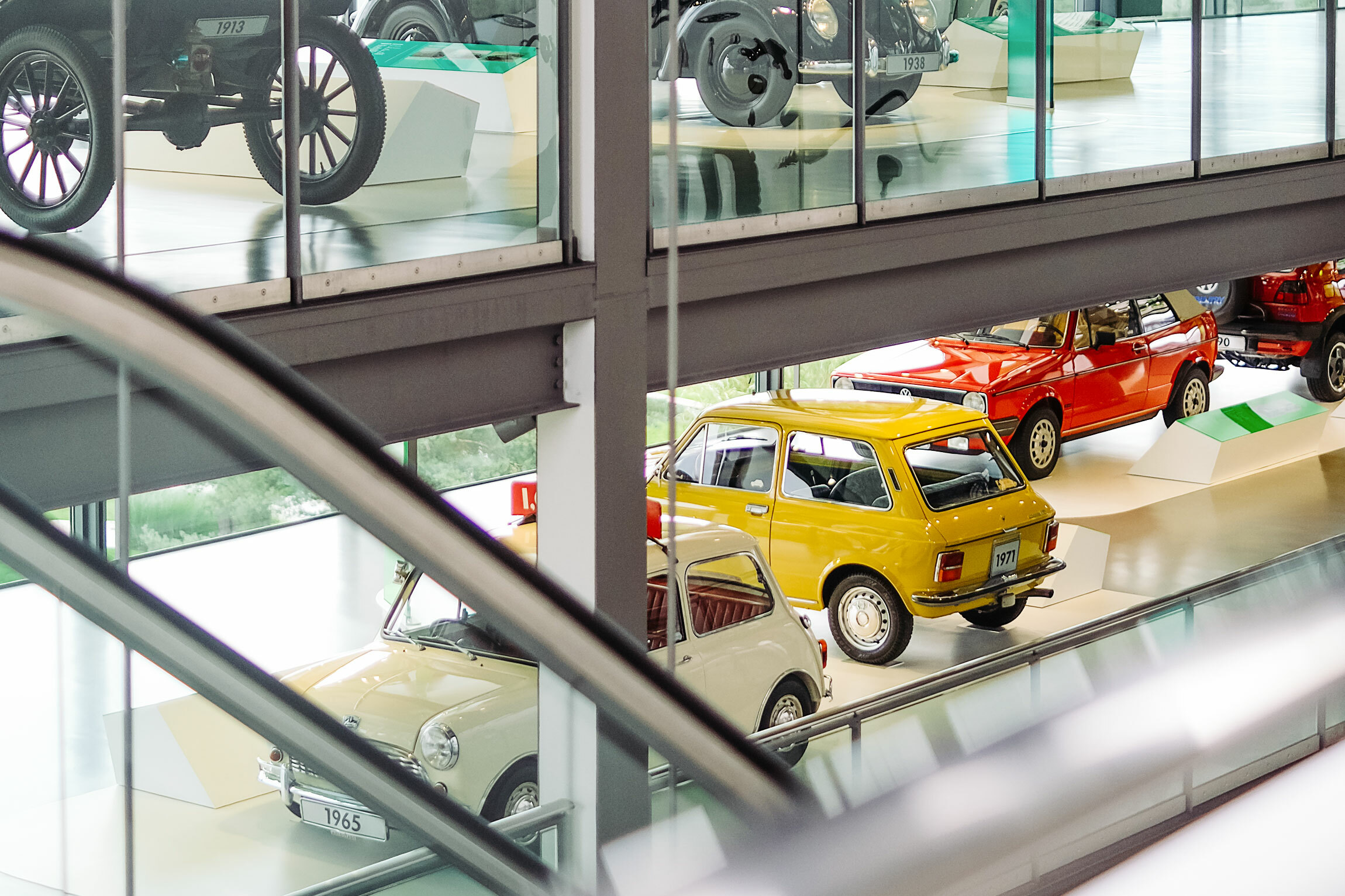 Foto in den Ausstellungsraum des Automuseums. Die Autos auf zwei sichtbaren Etagen haben Jahreszahlen auf den Nummernschildern.