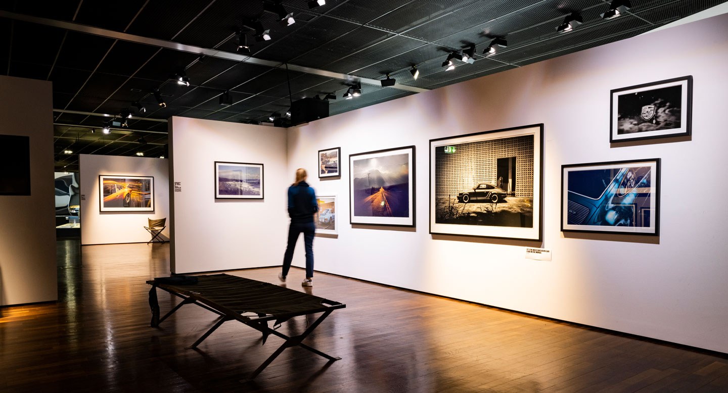 Foto eines Ausstellungsraumes in dem gerahmte Fotografien präsentiert werden. Eine Person steht im Raum, ist einem Bild zugewandt.